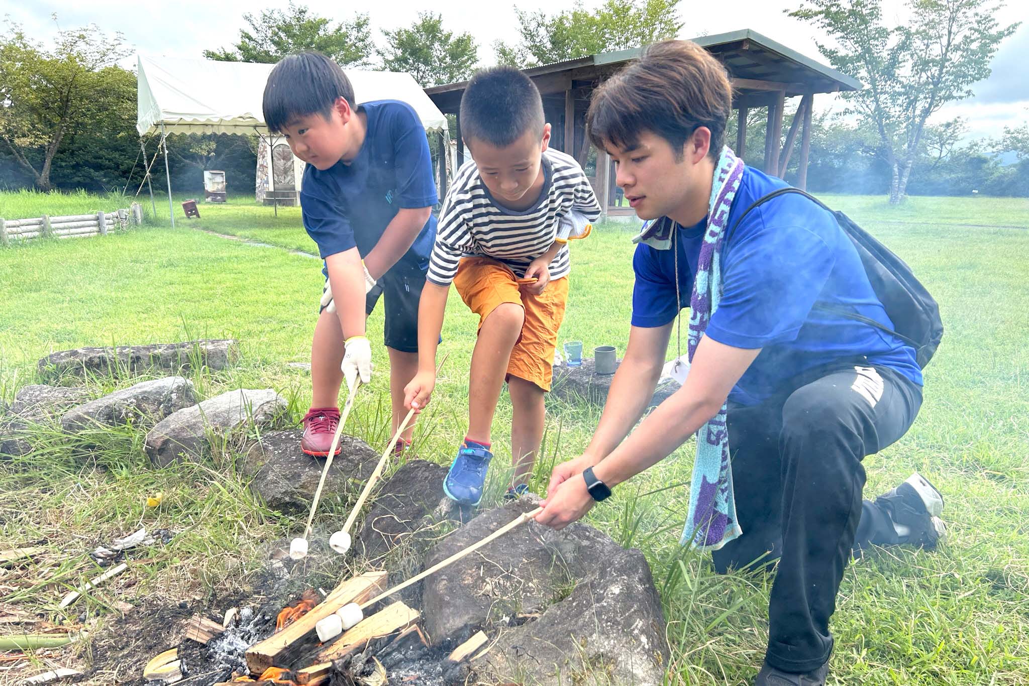 焚き火でマシュマロを焼いている子供達